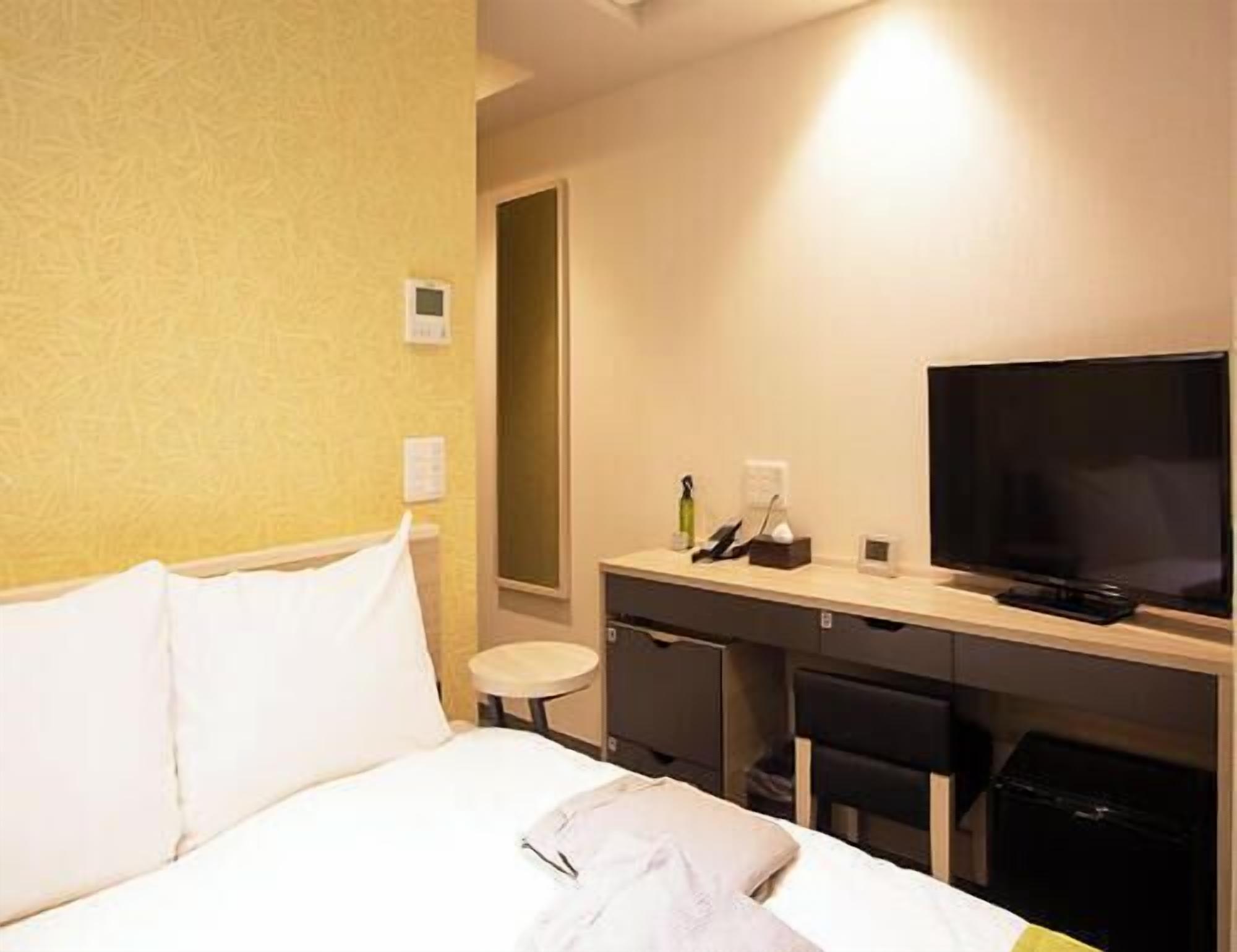 Ein Hotelzimmer mit Bett, Schreibtisch, Fernseher und Spiegel.