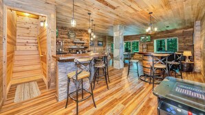A wooden interior with a bar area, bar stools, and a jukebox.