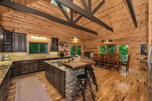 A spacious kitchen with a central island, stone accents, and a bar area with stools.