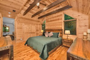 Camera da letto in una baita di legno, con un letto, comodini e una finestra con persiane.