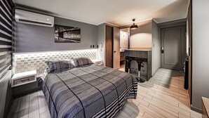 Een moderne slaapkamer met een bed, een nachtkastje, een wandairconditioner, een stadsgezicht kunstwerk en een houten vloer.