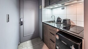 Een moderne keuken met een grijze deur, een zwart apparaat en een betegelde spatwand.