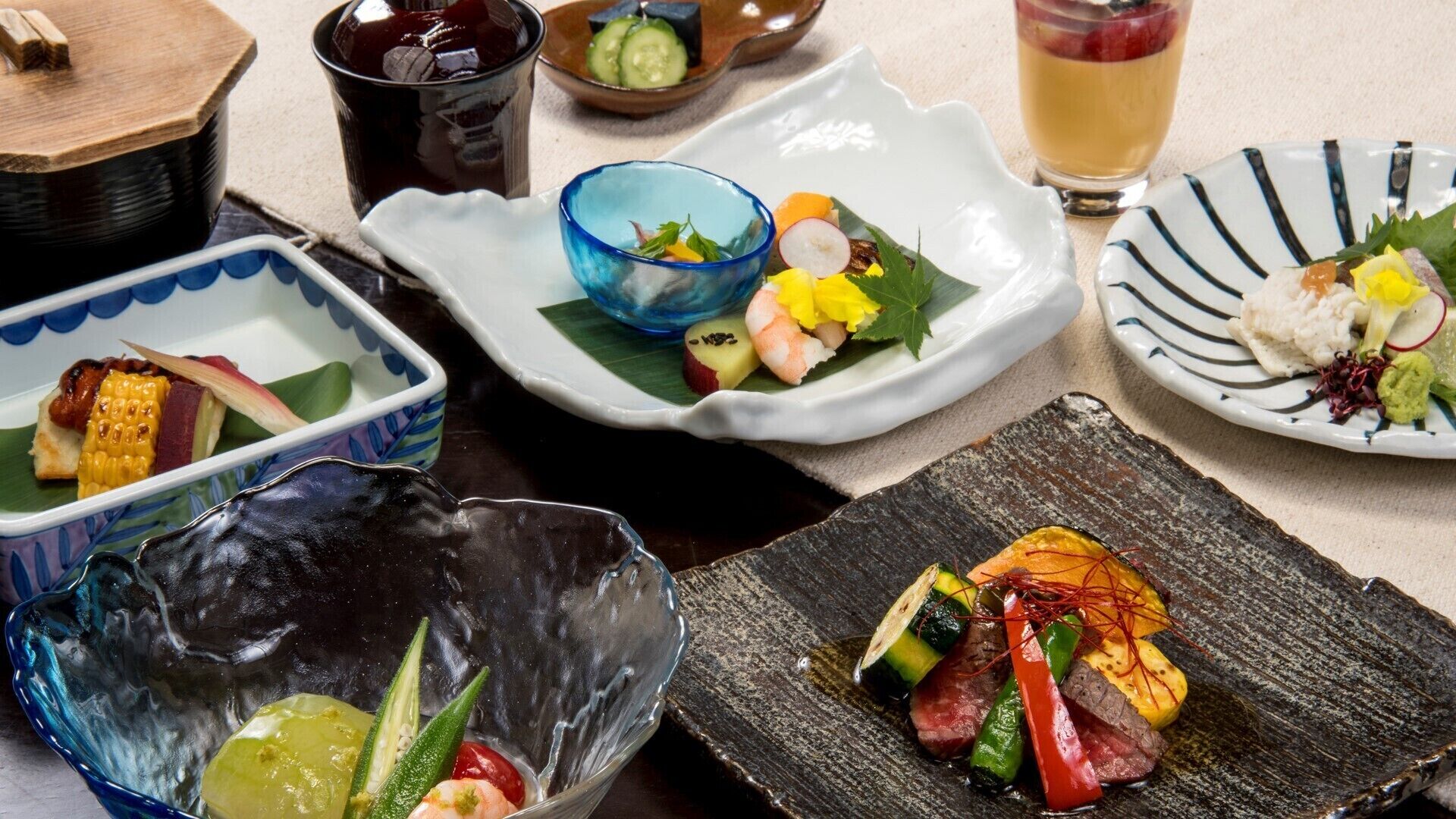 A variety of dishes including sushi, sashimi, and a bowl of vegetables.
