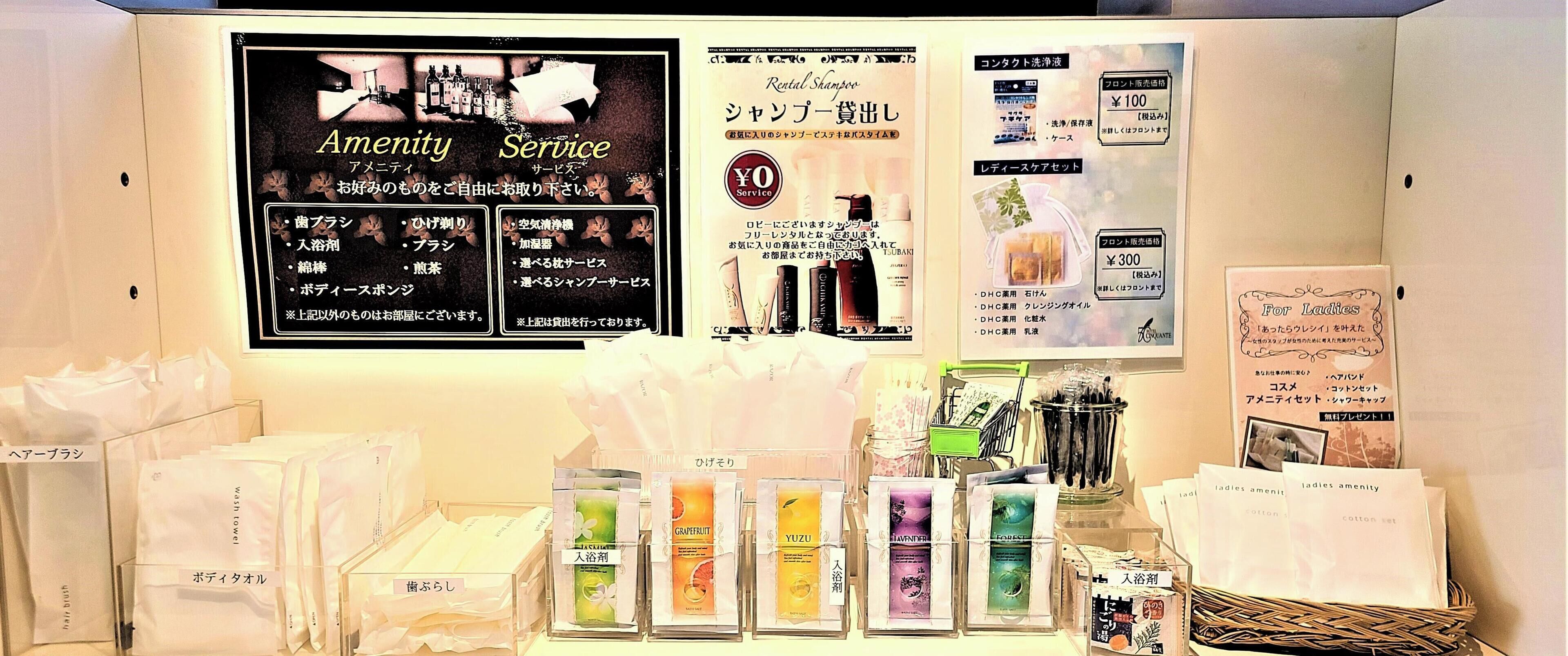 A hotel reception area with amenities like a rental shampoo service, a menu board, and various toiletries displayed on shelves.