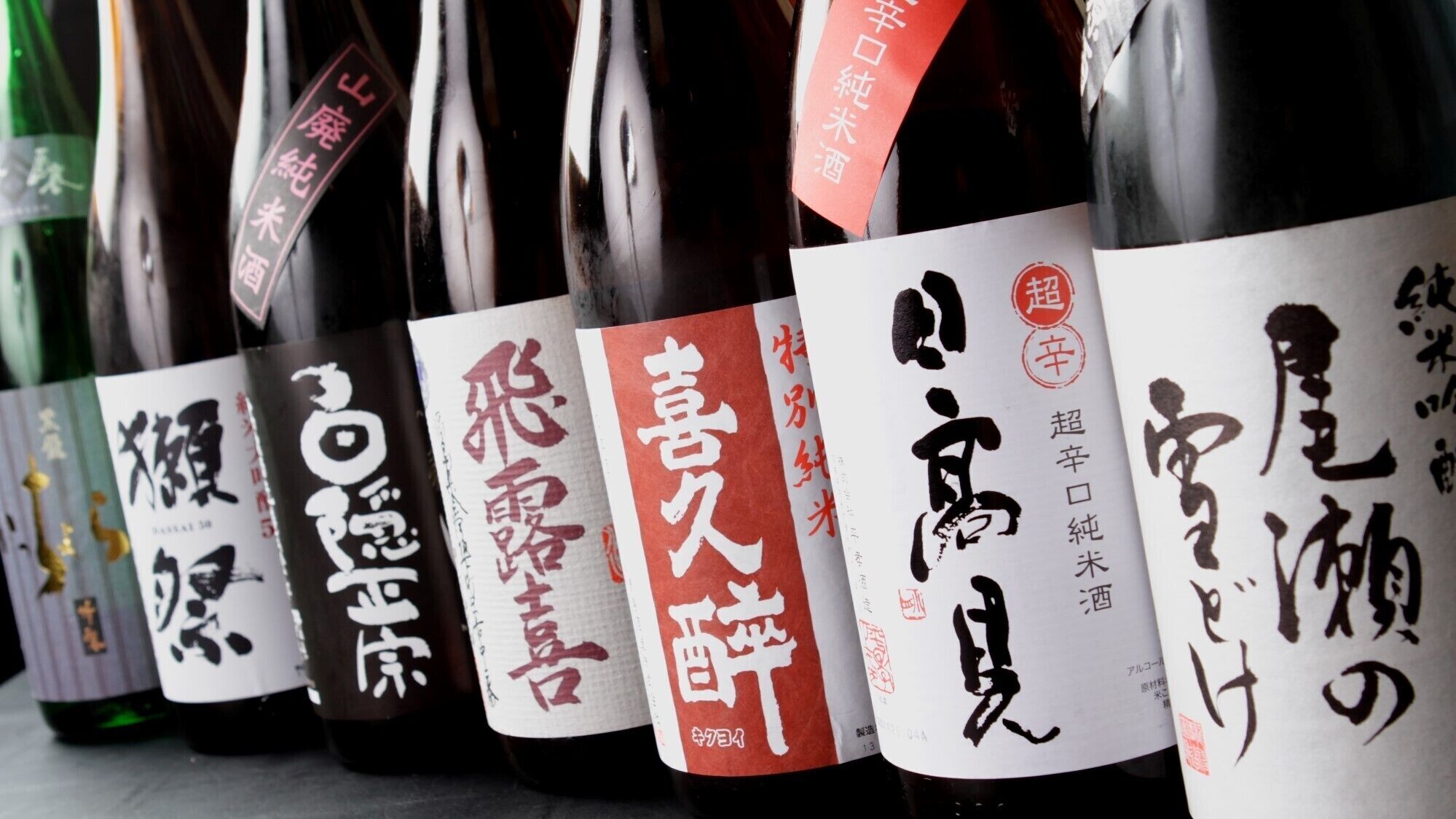 A row of wine bottles with labels featuring Japanese characters.