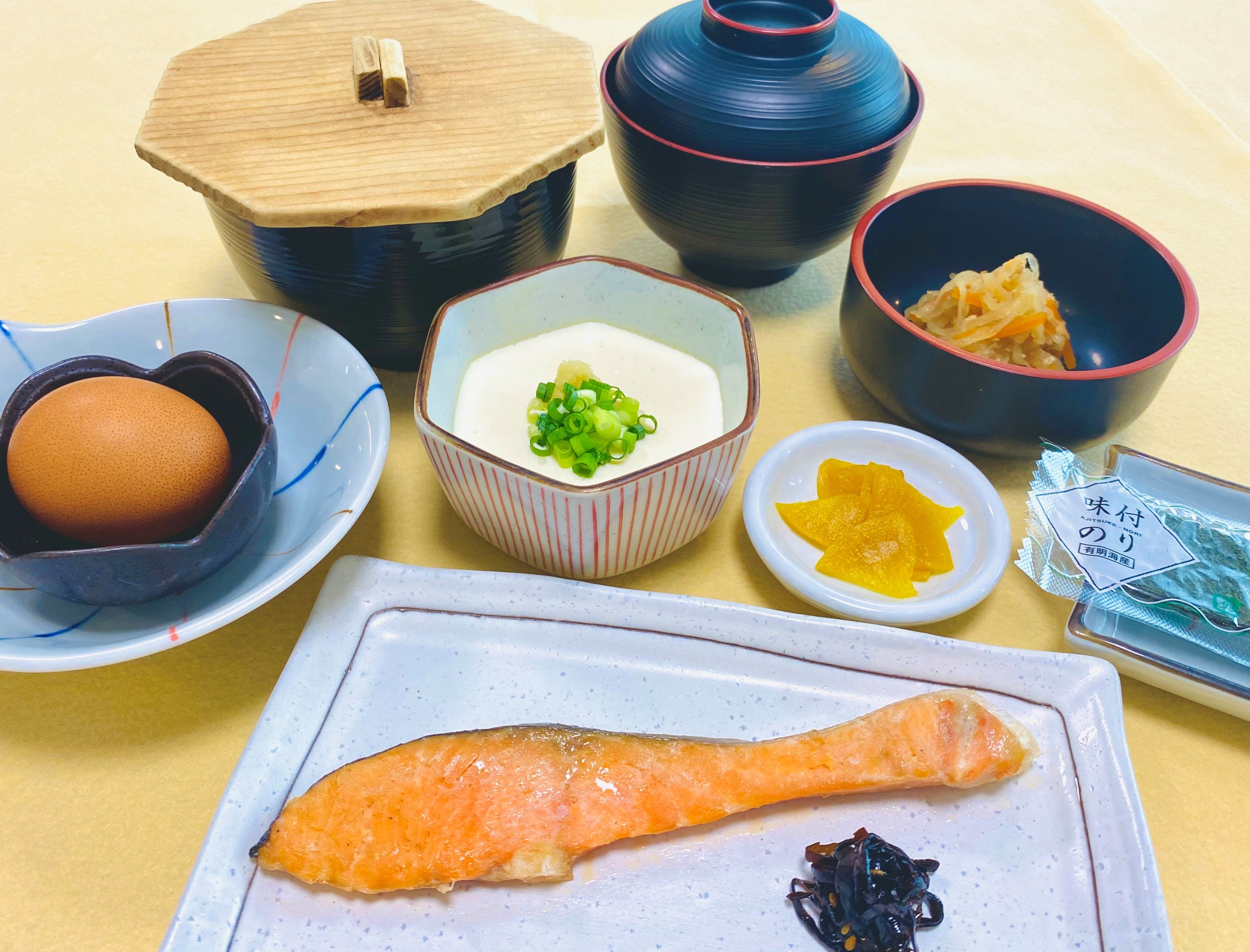 A variety of dishes including a bowl of soup, a plate with a piece of salmon, and several other bowls with different foods.