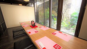 Un salón de conferencias con una larga mesa, sillas de cuero negro y un jarrón con flores.