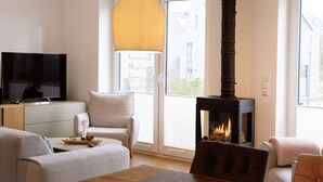 Een moderne woonkamer met een open haard, een televisie en comfortabele zithoek.