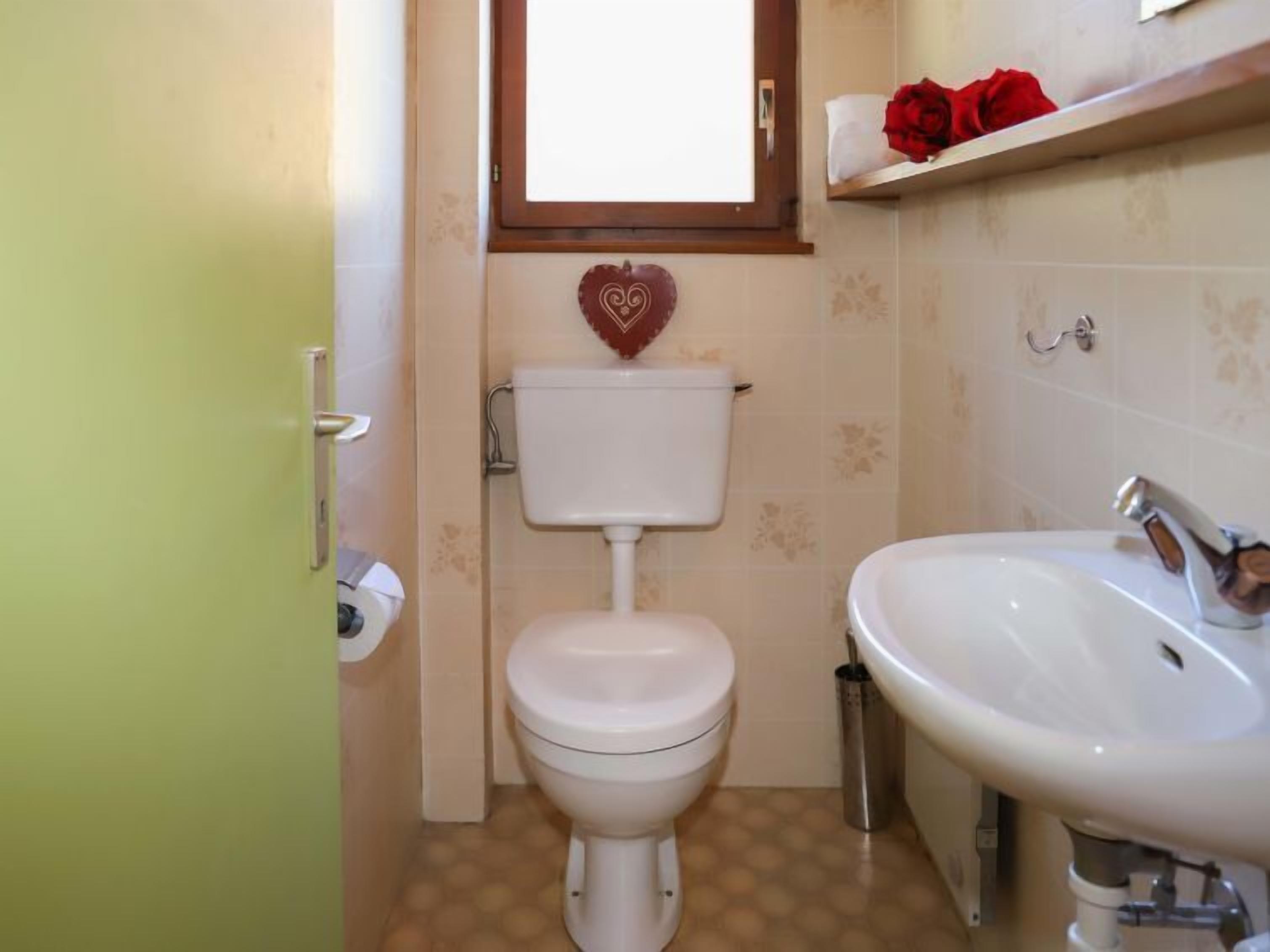 Une petite salle de bain avec des toilettes, un lavabo et une fenêtre située au-dessus des toilettes.