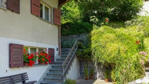 A stone staircase leading to a building with red shutters and a bench outside. - Strassscheuer by Interhome (Grindelwald)