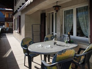 Une terrasse extérieure avec une table ronde, quatre chaises et un luminaire suspendu.