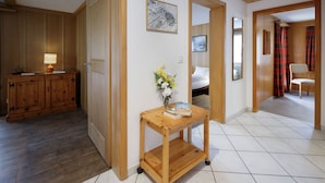 A hallway with a wooden cabinet, a small table with a vase of flowers, and a bed in the background. - Strassscheuer by Interhome (Grindelwald)
