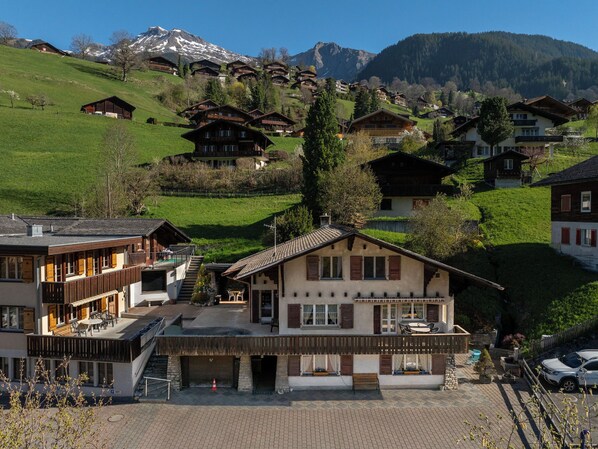 A hotel with a terrace, a mountain view, and traditional wooden architecture.
