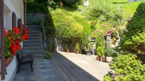 A stone-paved courtyard with a bench, potted plants, and a staircase leading to a building. - Strassscheuer by Interhome (Grindelwald)