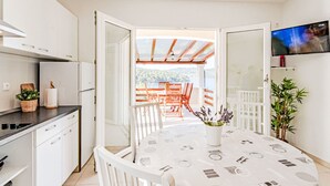 A modern kitchen with white cabinets, a black countertop, and a dining area with a table and chairs. - Vacation home Flora by Interhome (Korcula/Vela Luka)