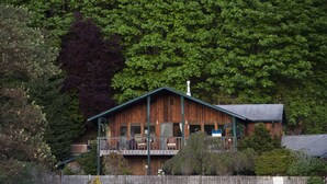 A wooden cabin with a balcony, surrounded by dense forest. - South Whidbey with water view, beach and hiking  (Clinton)