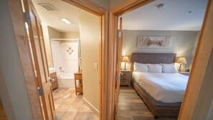 Ein Hotelzimmer mit Bett, Nachttischen, einer Lampe, einer Dusche und einem Badezimmer mit Handtuchhalter.