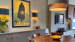 A dining area with a wooden table, chairs, a vase with sunflowers, and a framed poster on the wall. - Downtown MainStreet Penthouse 1BR five star Rental with parking overlooking main (Durango)