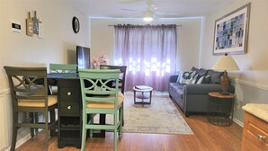 A living room with a dining area, a sofa, a lamp, and a ceiling fan.
