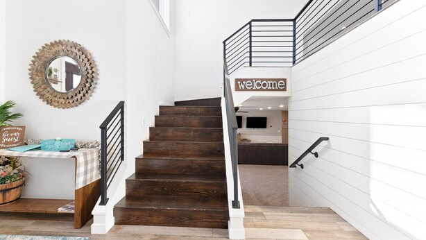 A staircase with a wooden finish, a black railing, and a 'welcome' sign at the top. - Roof Top Deck-Hot Tub-Steam Shower-Arcade Games-4car Garage-Chef`s Kitchen (Spearfish)