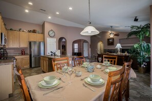 Enjoy meals in this dining area with a large table, modern kitchen, and cozy fireplace.
