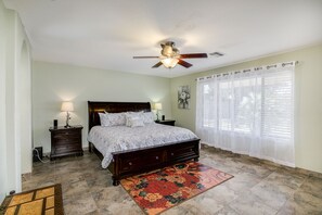 Cozy retreat with a large bed, two nightstands, and a ceiling fan, set against a light-colored backdrop.