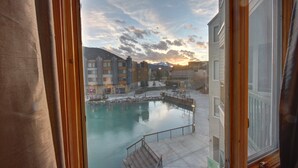 A view of a pool area with a wooden deck and a stone pathway leading to a building with multiple windows.