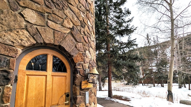 Un edificio de piedra con una puerta de madera, un muro de piedra y un sendero cubierto de nieve.