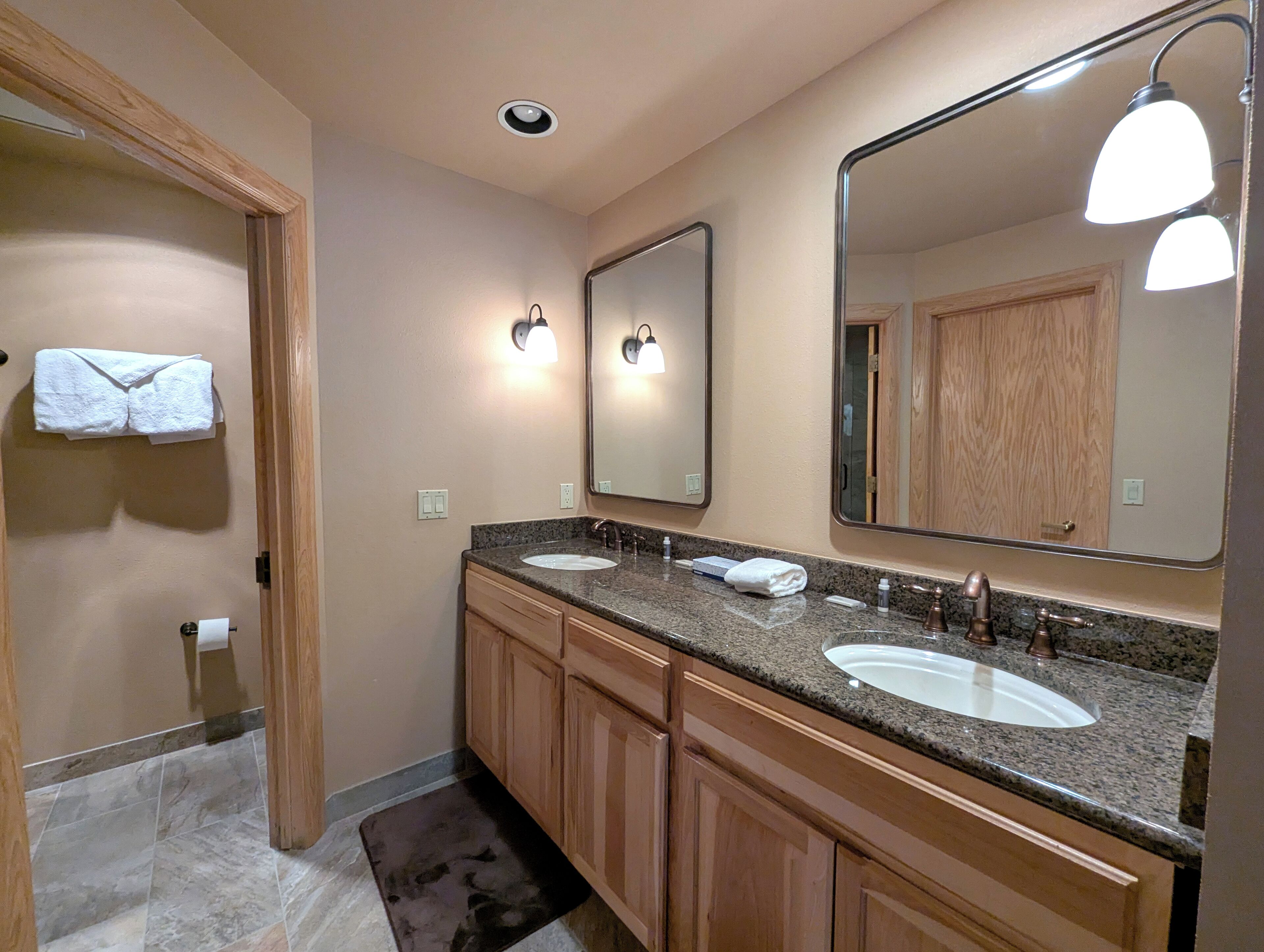 A bathroom with two sinks, wooden cabinets, a large mirror, and a towel rack.