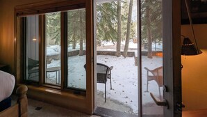 Una habitación con un amplio ventanal corredero que da a un espacio exterior nevado con árboles y un banco.