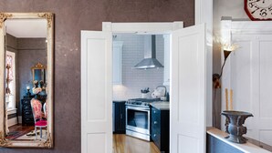 A kitchen with a white tiled backsplash, a stainless steel oven, and a hanging light fixture. - Bright, Historic Row Home Minutes from Forsyth by Lucky Savannah (Savannah)