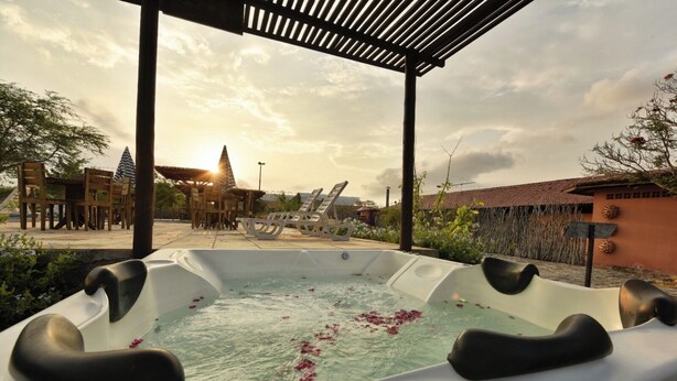 Un bain à remous avec vue sur un bâtiment traditionnel et un coucher de soleil en arrière-plan.