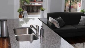 A modern kitchen with granite countertops, stainless steel appliances, and a black sofa with a cushion.