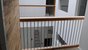A multi-level interior with a wooden floor, white walls, and a metal railing.