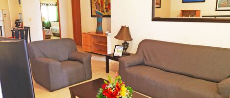 A living room with two sofas, a coffee table with a floral arrangement, a TV, and a fireplace.