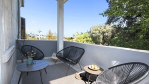 En balkon med to stole, et lille bord og en potteplante.