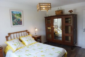 A bedroom with a wooden bed, a nightstand, a cabinet with glass doors, and a hanging light fixture.