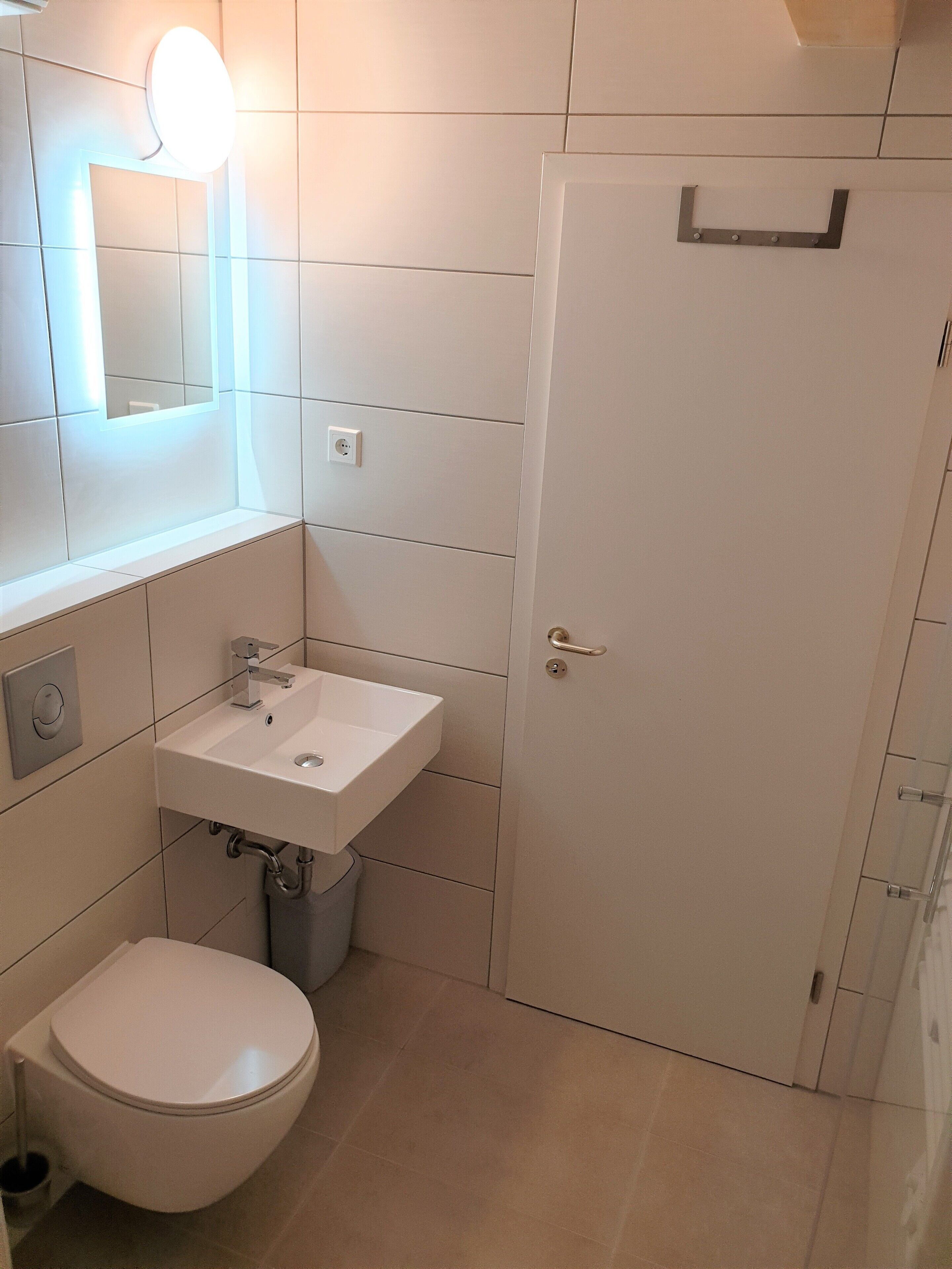 Ein modernes Badezimmer mit Toilette, Waschbecken und Spiegel.