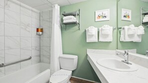 A bathroom with a shower, toilet, sink, and towel rack.