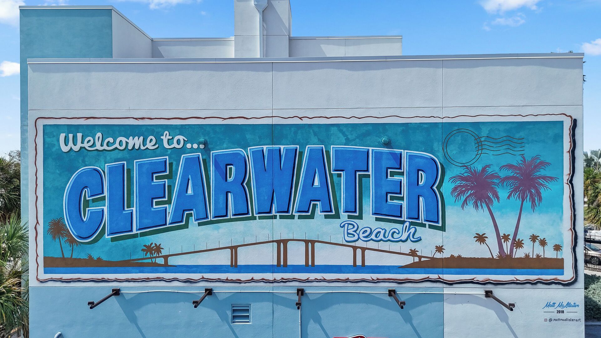 A mural welcoming visitors to Clearwater Beach, featuring palm trees and a bridge.
