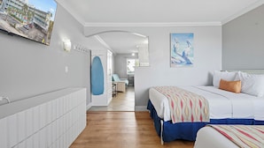 A hotel room with a bed, a blue chair, a painting, and a view of the street.