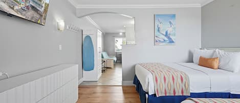 Ein Hotelzimmer mit einem Bett, einem blauen Sessel, einem Gemälde und Blick auf die Straße.