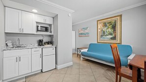 A compact living space with a kitchenette, a blue sofa, and a dining table.