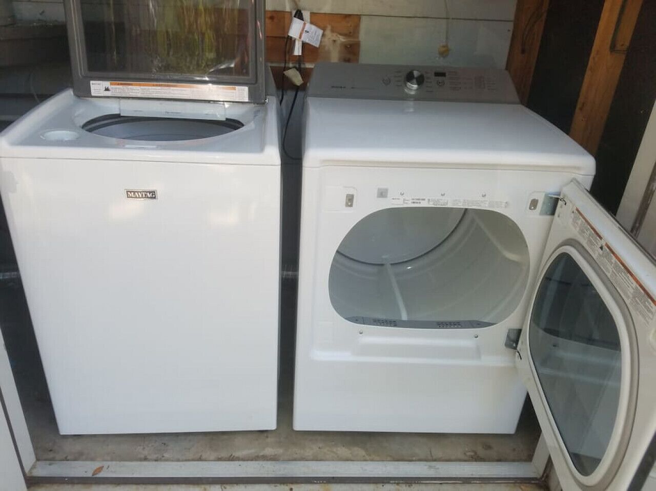 A compact laundry room with two white washing machines, one with a front-loading door and the other with a top-loading door.