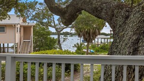 A house with a deck overlooking a lake, surrounded by trees. - Hook, Wine & Sinker Cottage: Water Views, Kayaks, Bikes & Old Florida Charm (Cedar Key)