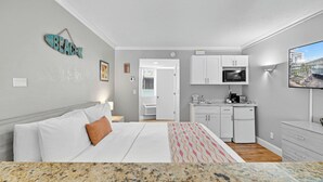 Una camera d'albergo con un letto, angolo cottura, bagno e televisione.