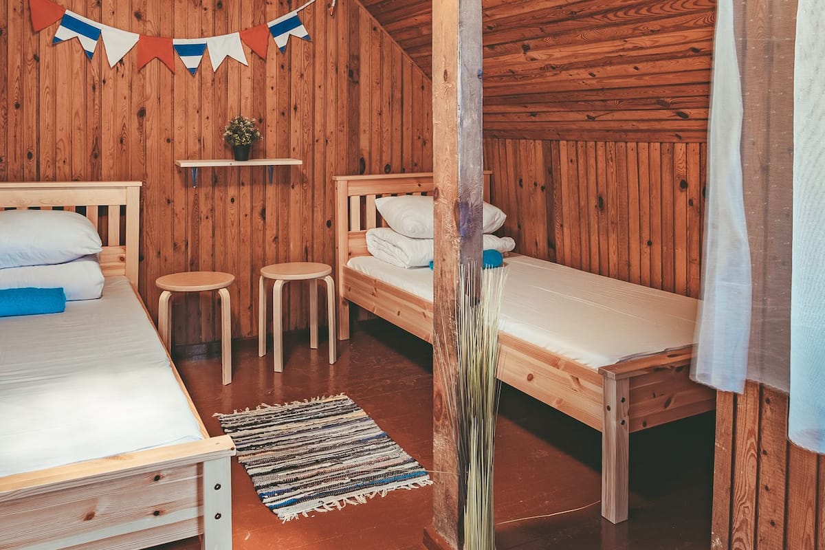 A cozy wooden room with two beds, a hanging light fixture, and a small table.