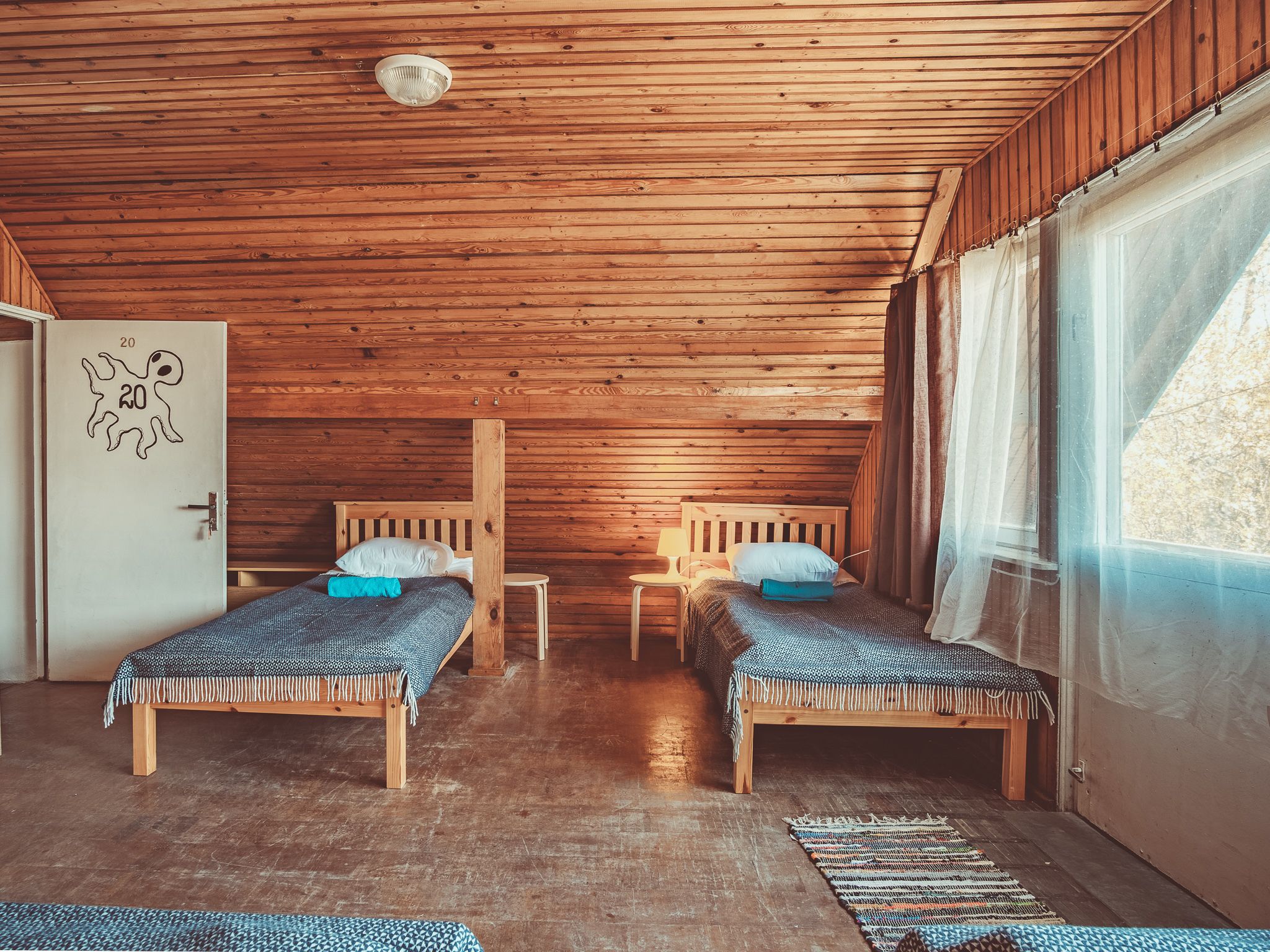 A cabin with two wooden beds, a small table, and a door marked with the number 20.
