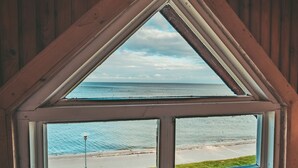 A triangular window with a view of the beach and ocean. - Guboja (Neringa)
