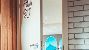 A hotel room with a wooden door, a view of the sea through a window, and a brick wall. - Guboja (Neringa)
